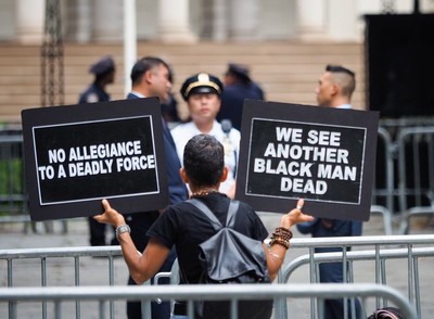 A woman holds signs in front of police officers as she joins a rally at City Hall Park in downtown Manhattan on Aug. 1, 2016. (Anthony DelMundo/New York Daily News)